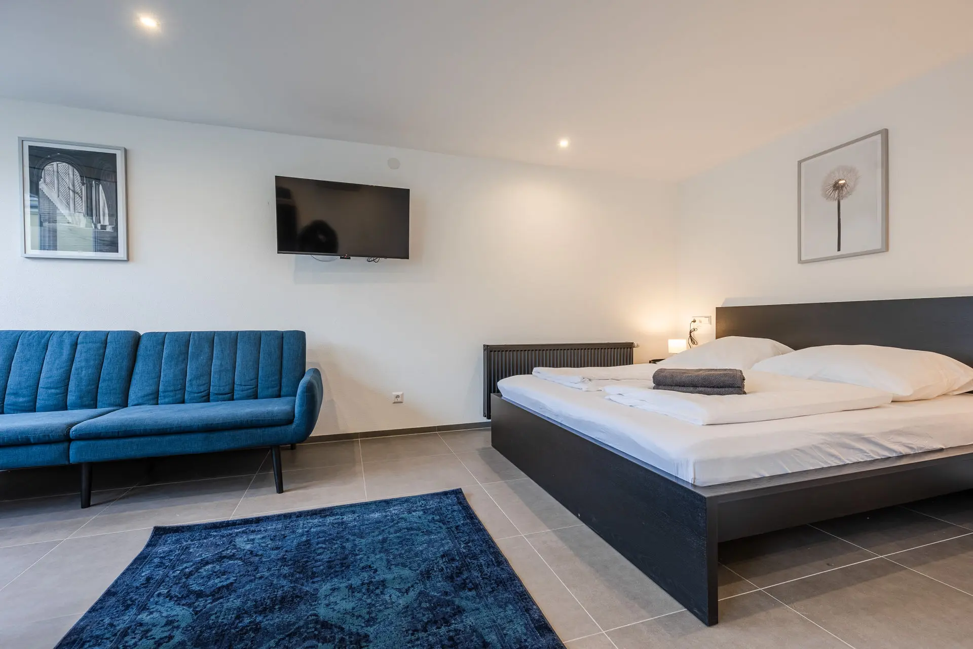 Schlafbereich mit großem Doppelbett und blauem Schlafsofa